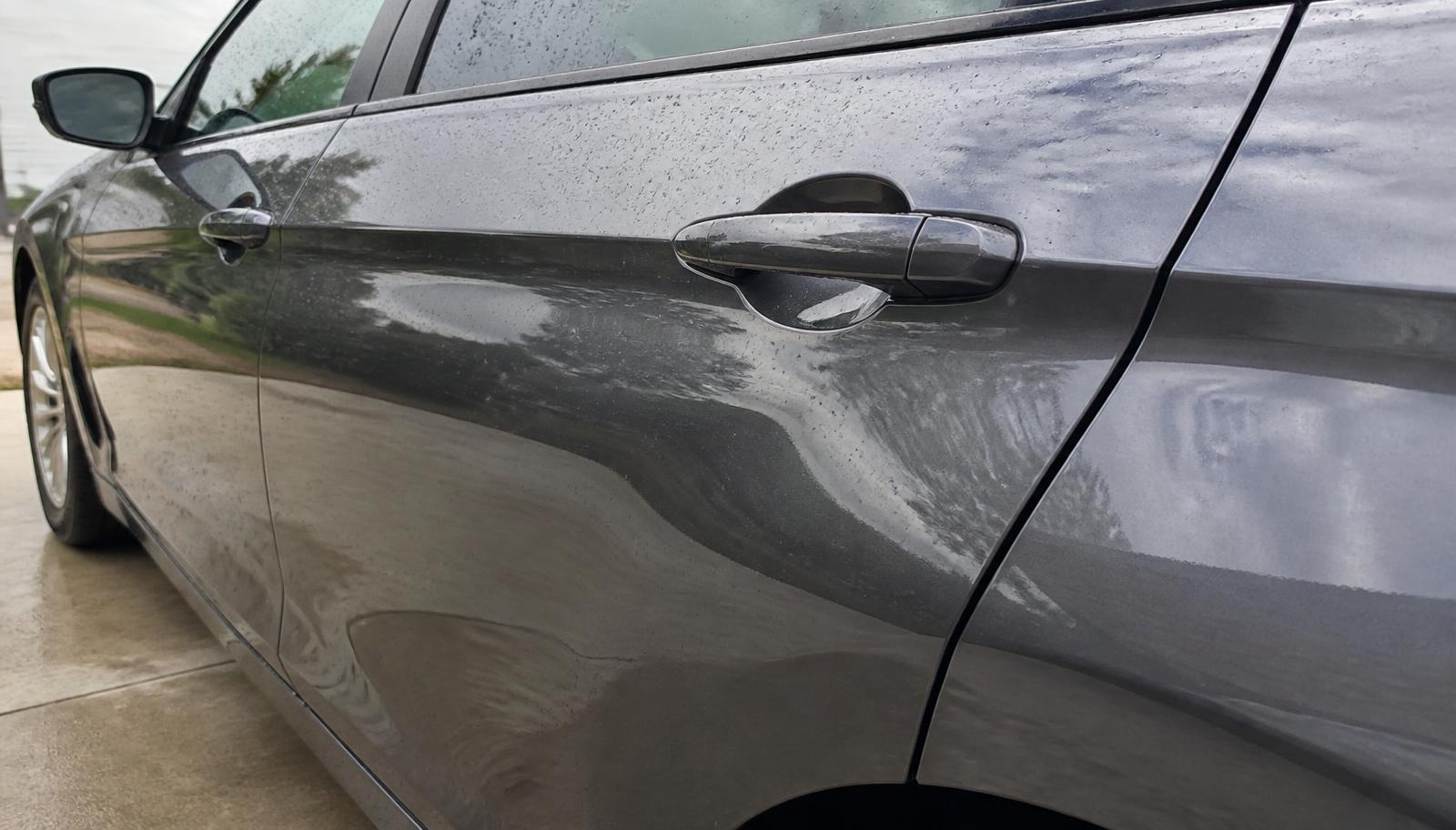The side of a clean dark grey car with an even glossy finish and crisp reflections after washing.