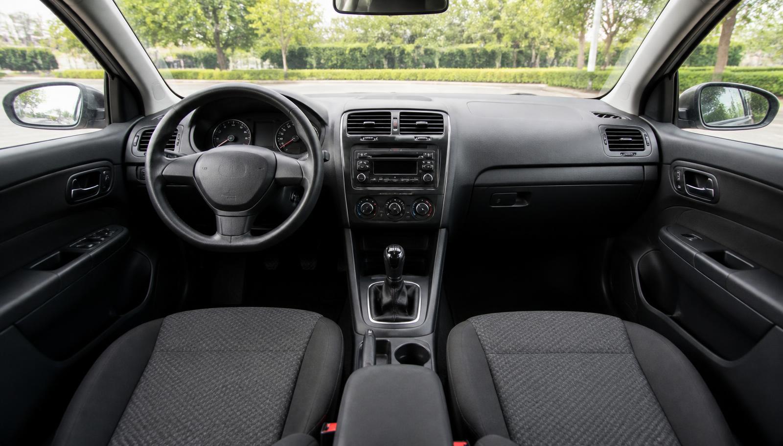 The clean interior of an ordinary family car: wiped dashboard, centre console and vacuumed cloth seats.